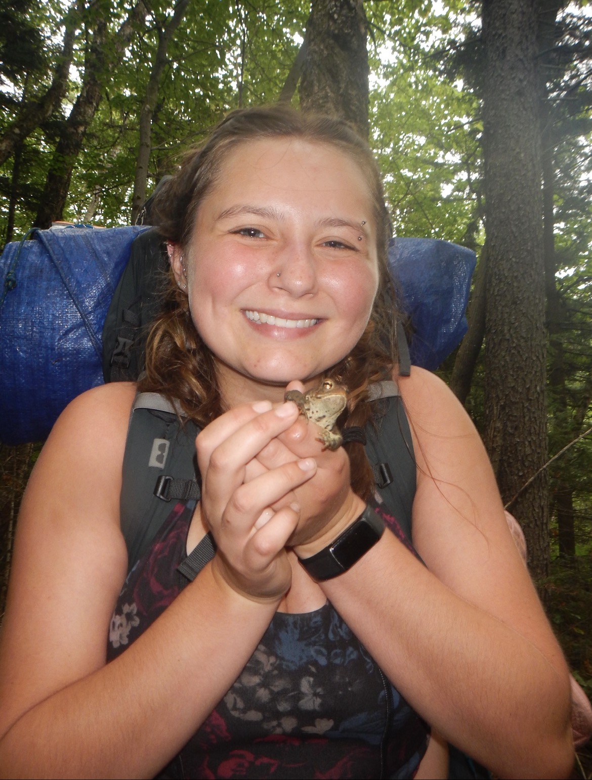 Savanna on a BOLT backpacking trip, holding a toad in both her hands and smiling big for the camera!